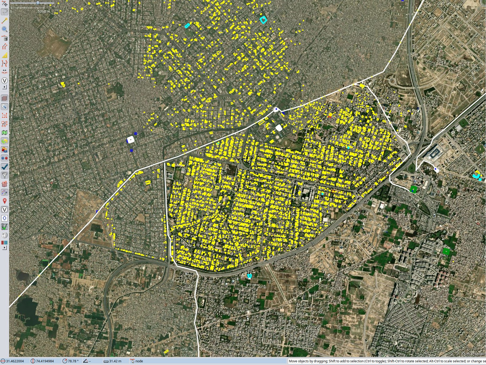 A JOSM window over eastern Lahore. Thousands of small yellow polygons, one per mapped rooftop PV installation, fill two neighbourhoods so densely that the street grid shows through them, and the mapped area stops sharply along a ring road and a railway line, beyond which identical-looking suburbs carry almost no yellow.